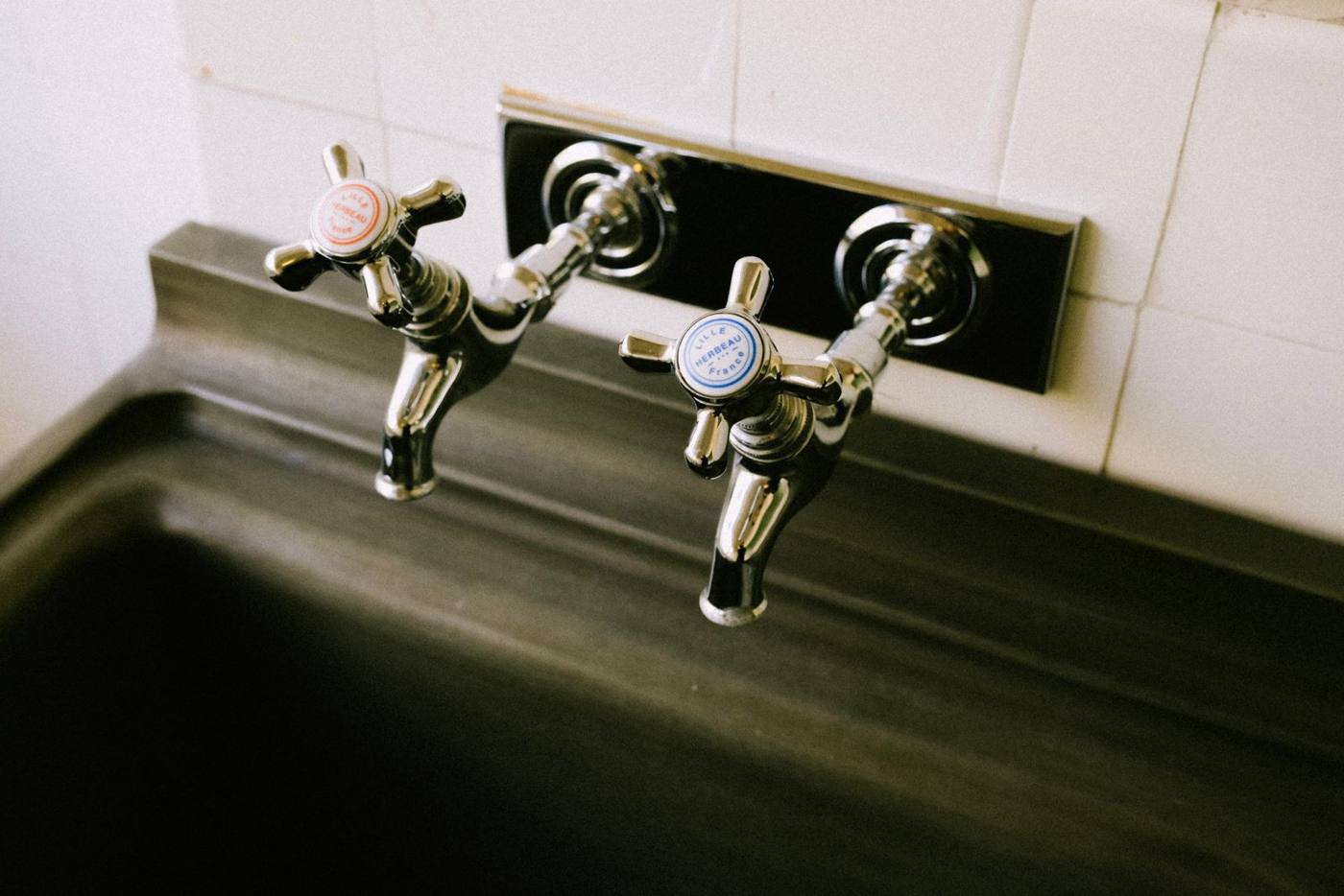 Two chrome faucets over a utility sink